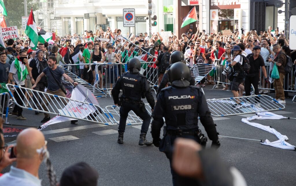 Manifestantes propalestinos tiran las vallas de seguridad de la Vuelta a la altura de Callao ante varios policías.