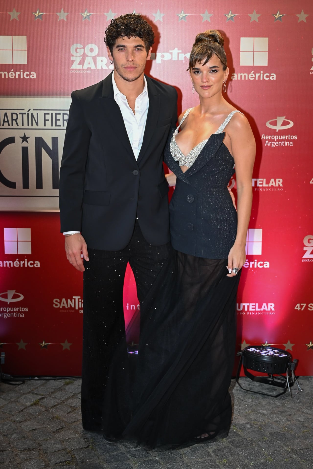 El Purre apostó por un esmoquin negro de líneas modernas y camiseta con leve escote. Malena Ratner, por su lado, eligió un vestido con falda translúcida y escote profundo adornado con apliques plateados