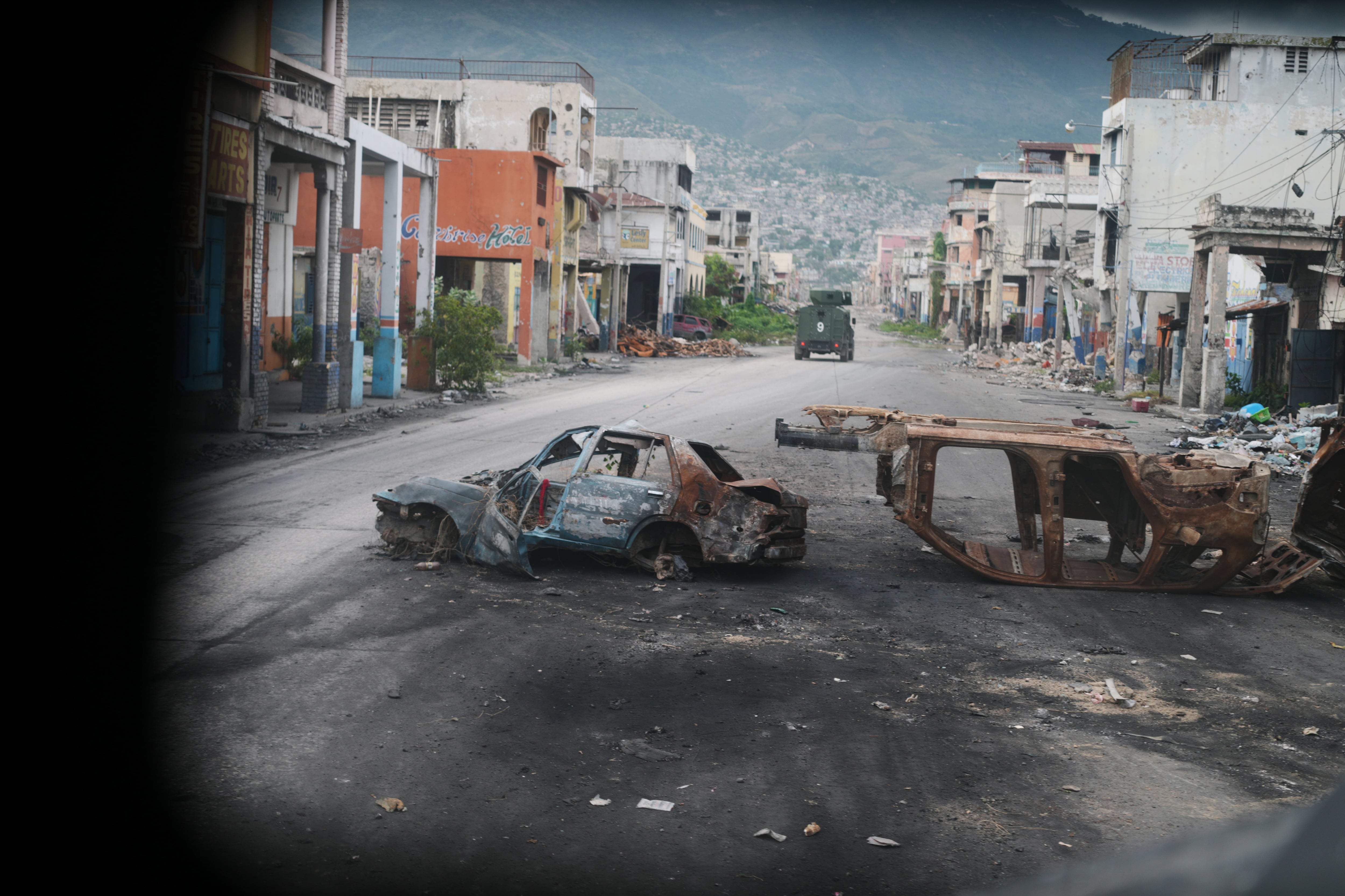 Carros chamuscados bloquean una calle, fotografiada desde un vehículo policial blindado que patrullaba una zona de Puerto Príncipe afectada por pandillas, el 16 de enero del 2026 (AP foto/Odelyn Joseph)