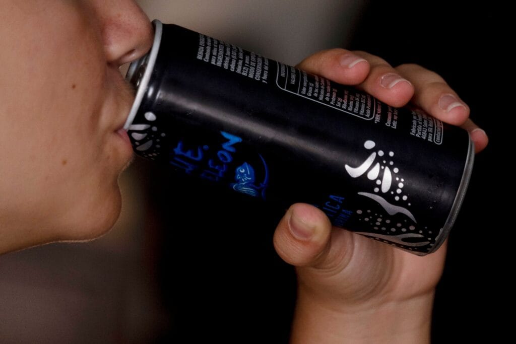 Una joven toma una lata de una bebida energética.