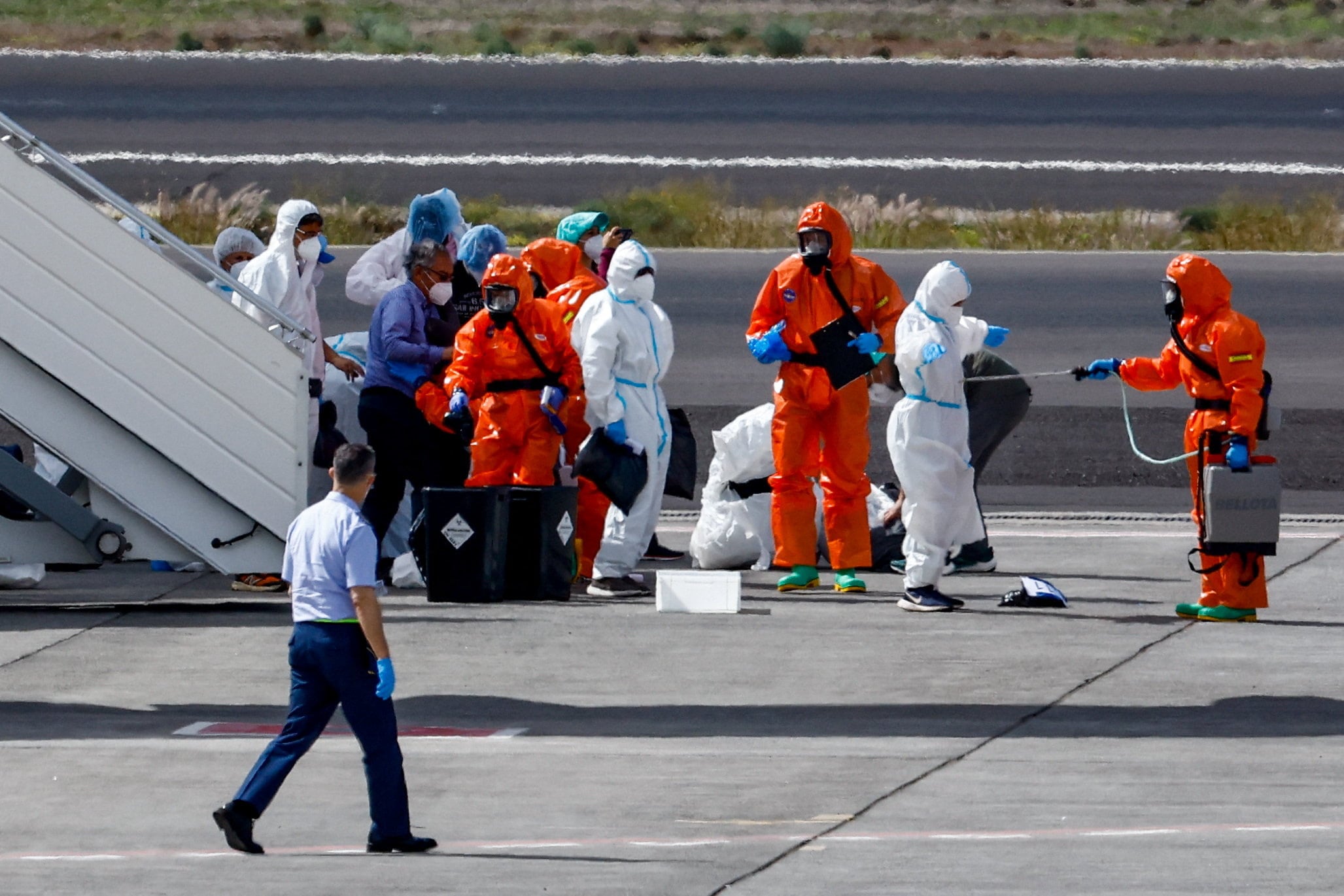 Personas equipadas con material de protección personal realizan los preparativos en la pista del aeropuerto de Tenerife Sur, tras la llegada del crucero MV Hondius, afectado por un brote de hantavirus, Islas Canarias, España, 10 de mayo de 2026. (REUTERS/Borja Suárez)