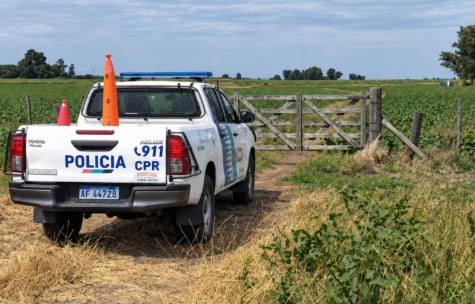 Un patrullero de la policía rural permanece en la entrada del campo donde un joven falleció a causa de un disparo accidental. (FM La Marea)